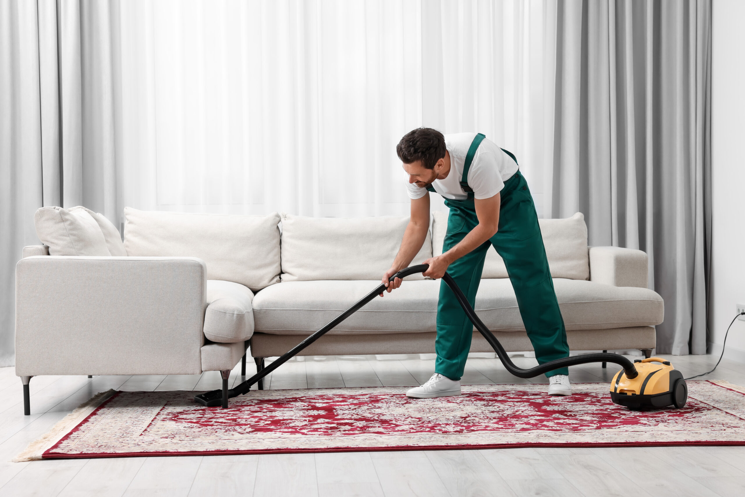 Man vacuuming red carpet in living room